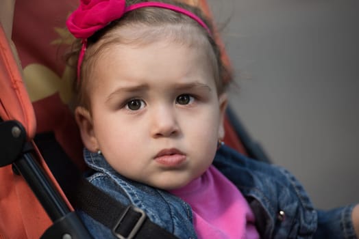 little and very beautiful baby girl sitting in the pram and waiting for mom