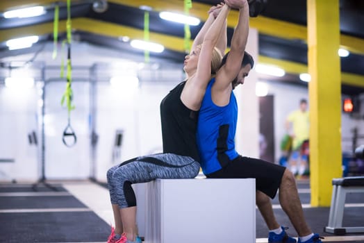young couple athletes working out their arms using boxes at cross fitness gym