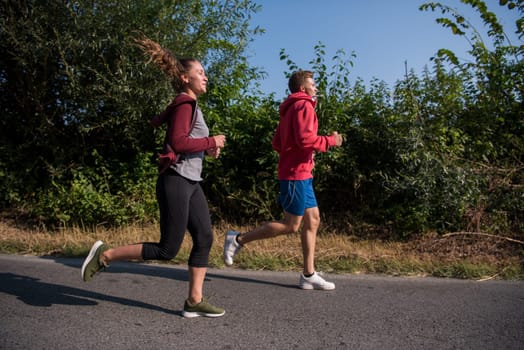 young couple enjoying in a healthy lifestyle while jogging along a country road, exercise and fitness concept