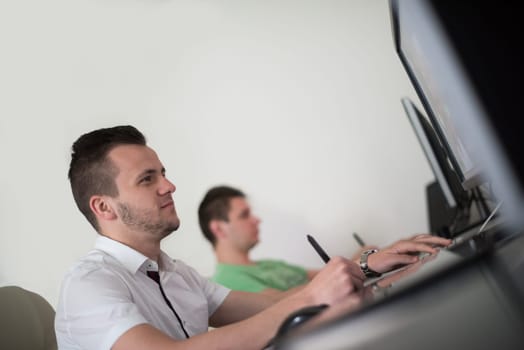 a group of young graphic designers working on a digital tablet and a computer