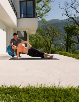 young handsome woman with personal trainer doing morning yoga exercises in front of her luxury home villa