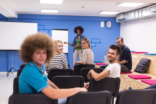 Portrait of smiling young informal businessman with colleagues in background at the office