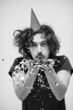 young man celebrating new year and chrismas party while blowing confetti decorations to camera