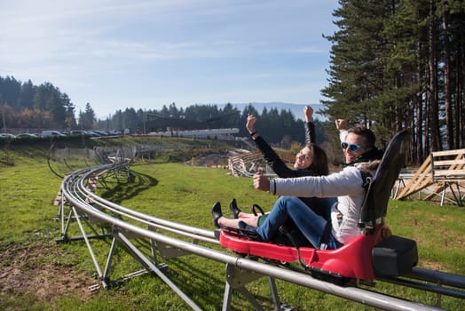 Excited young couple enjoys driving on alpine coaster