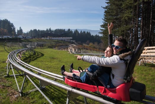 Excited young couple enjoys driving on alpine coaster