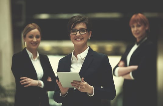 young business woman group,  team standing in modern bright office and working on tablet computer