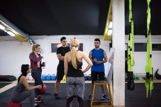 Training course.group of young athletes getting instructions from trainer before exercise at cross fitness gym