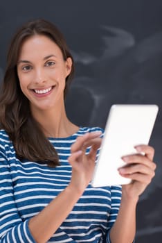 Happy young woman using tablet computer in front of chalk drawing board