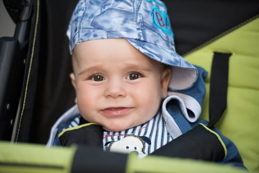 little and very beautiful baby boy sitting in the pram and waiting for mom