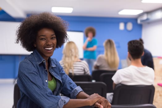 portrait of young African American business woman at modern startup office interior, team in meeting in background