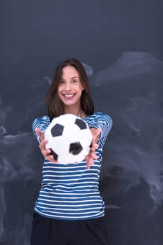portrait of a young woman holding a soccer ball in front of chalk drawing board