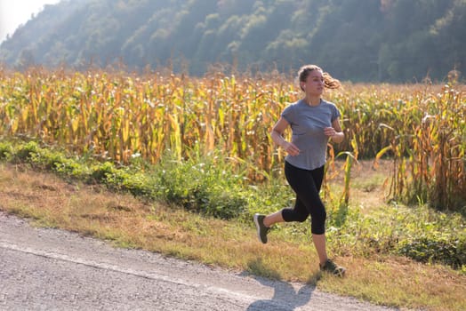 young woman enjoying in a healthy lifestyle while jogging along a country road, exercise and fitness concept