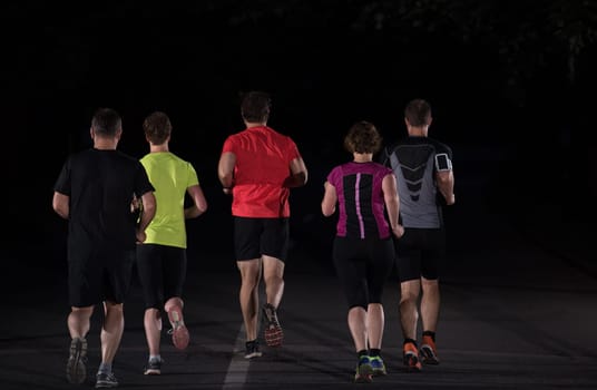 group of healthy people jogging in city park, runners team at night training