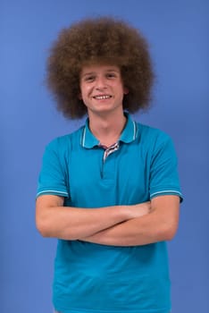 portrait of a young man with a funky hairstyle with arms crossed on blue background