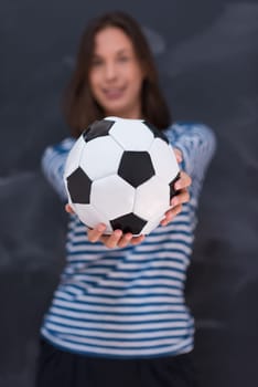 portrait of a young woman holding a soccer ball in front of chalk drawing board