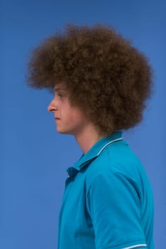 portrait of a young man with a funky hairstyle with arms crossed on blue background