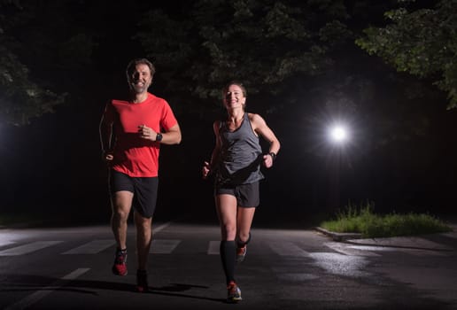 group of healthy people jogging in city park, runners team at night training