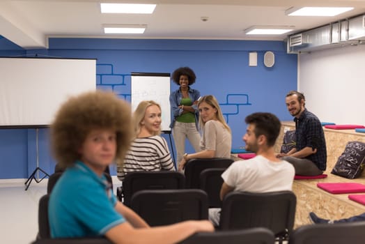 Portrait of smiling young informal businessman with colleagues in background at the office