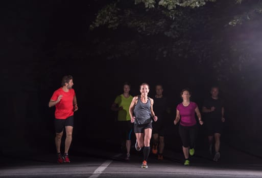 group of healthy people jogging in city park, runners team at night training
