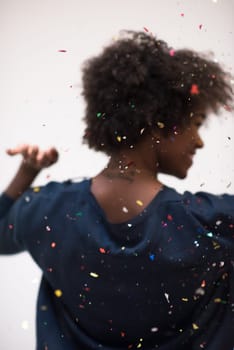 beautiful young black woman celebrating new year and chrismas party while blowing confetti decorations to camera