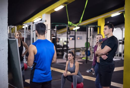 Training course.group of young athletes getting instructions from trainer before exercise at cross fitness gym