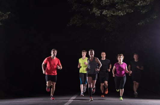 group of healthy people jogging in city park, runners team at night training