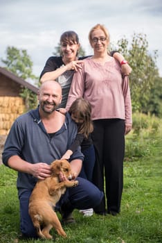 portrait of happy three generations family with dog at beautiful countryside farm