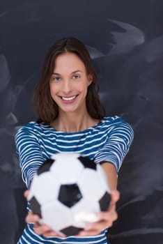 portrait of a young woman holding a soccer ball in front of chalk drawing board