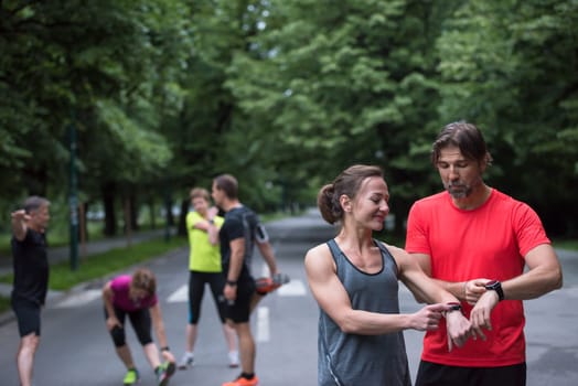 Young sporty couple using smart watches starting their timer before jogging