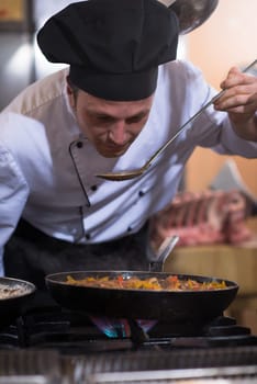 Handsome chef tasting food with spoon at the  restaurant kitchen