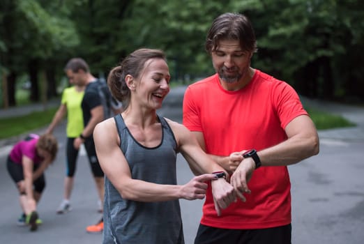Young sporty couple using smart watches starting their timer before jogging