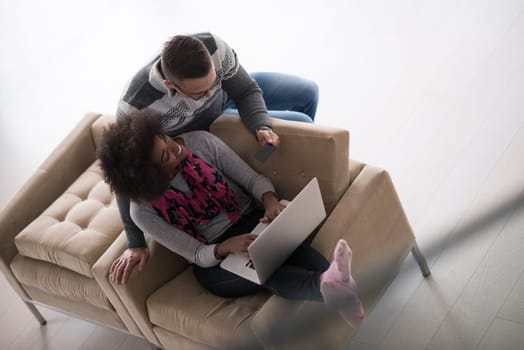 Happy young multiethnic couple shopping online through laptop using credit card at home
