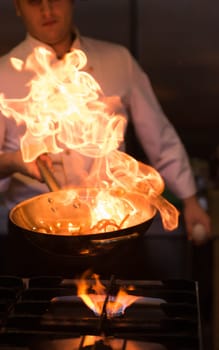 Chef cooking and doing flambe on food in restaurant kitchen
