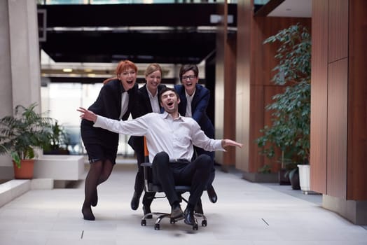 business people group at modern office indoors have fun and push office chair on corridor