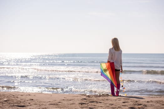 Beautiful Young Woman having fun with a kite at Beach on autumn day