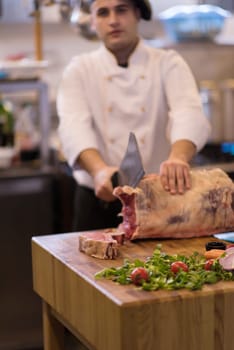 chef using ax while cutting big piece of beef  on wooden board in restaurant kitchen