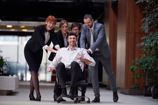 business people group at modern office indoors have fun and push office chair on corridor