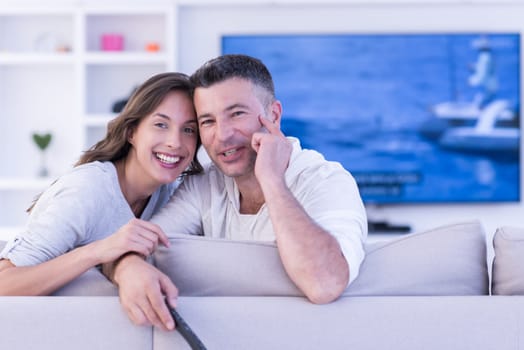 Young couple on the sofa watching television together in their luxury home