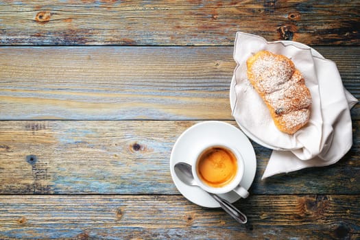View from above. Cup of hot Italian espresso coffee and croissants on a light blue rustic wooden background. Food and drink. Lifestyle.