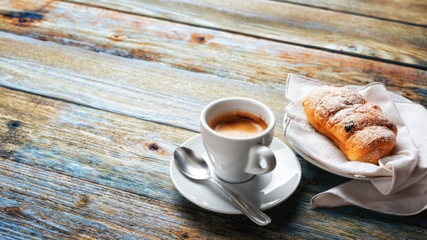 View from above. Cup of hot Italian espresso coffee and croissants on a light blue rustic wooden background. Food and drink. Lifestyle.