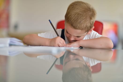 young mom woman doing home work with elementary school grade boy at home in kitchen