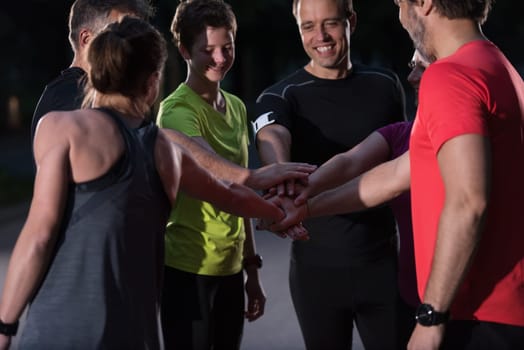 Group of healthy runners giving high five to each other while celebrating success after a training session.