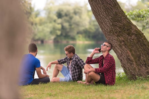 Group of young  men enjoying the nature sitting on the bank of the river