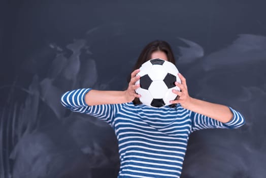 portrait of a young woman holding a soccer ball in front of chalk drawing board