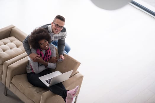 Happy young multiethnic couple shopping online through laptop using credit card at home