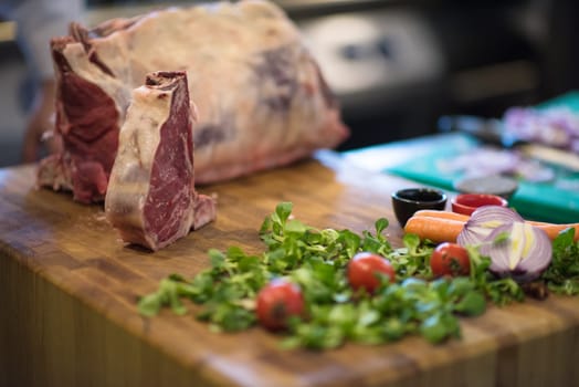 Juicy slice of raw steak  with vegetables around on a wooden table