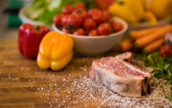 Juicy slice of raw steak  with vegetables around on a wooden table