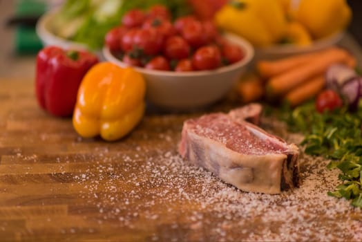 Juicy slice of raw steak  with vegetables on a wooden table