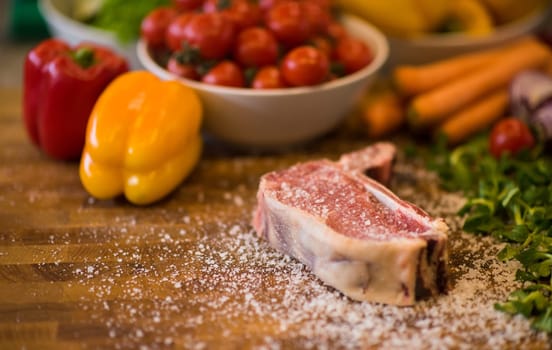 Juicy slice of raw steak  with vegetables around on a wooden table