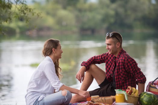 Couple in love enjoying picnic time drink and food in beautiful nature on the river bank